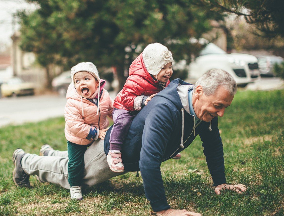 Grandfather playing with his grandchildren in the grass